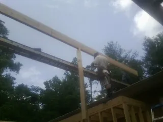 Carpenter setting a ridge beam over a new addition frame — Ice Dam Removal by Roofing Brothers in Killduff