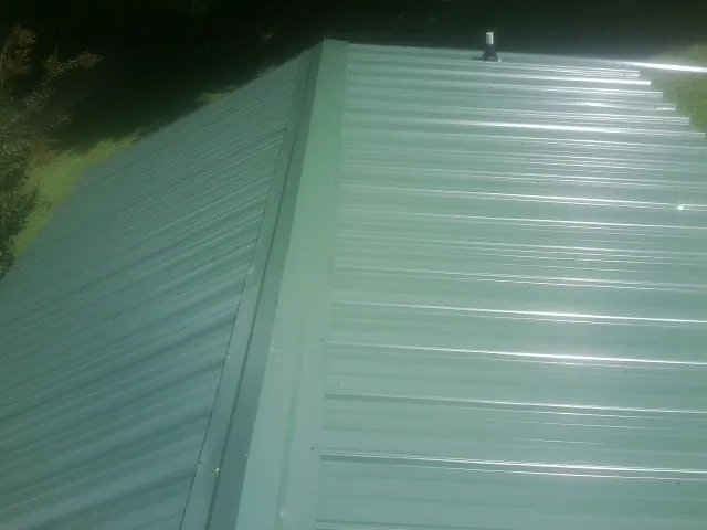 New green metal panels meeting at the ridge of a roof — Flat Roof Repair work by our crew in Killduff