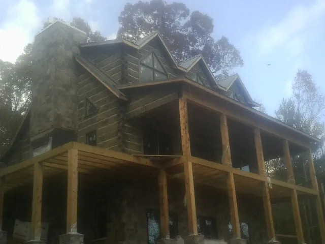 Stone chimney and dormers on a large log home with a timber porch in Killduff
