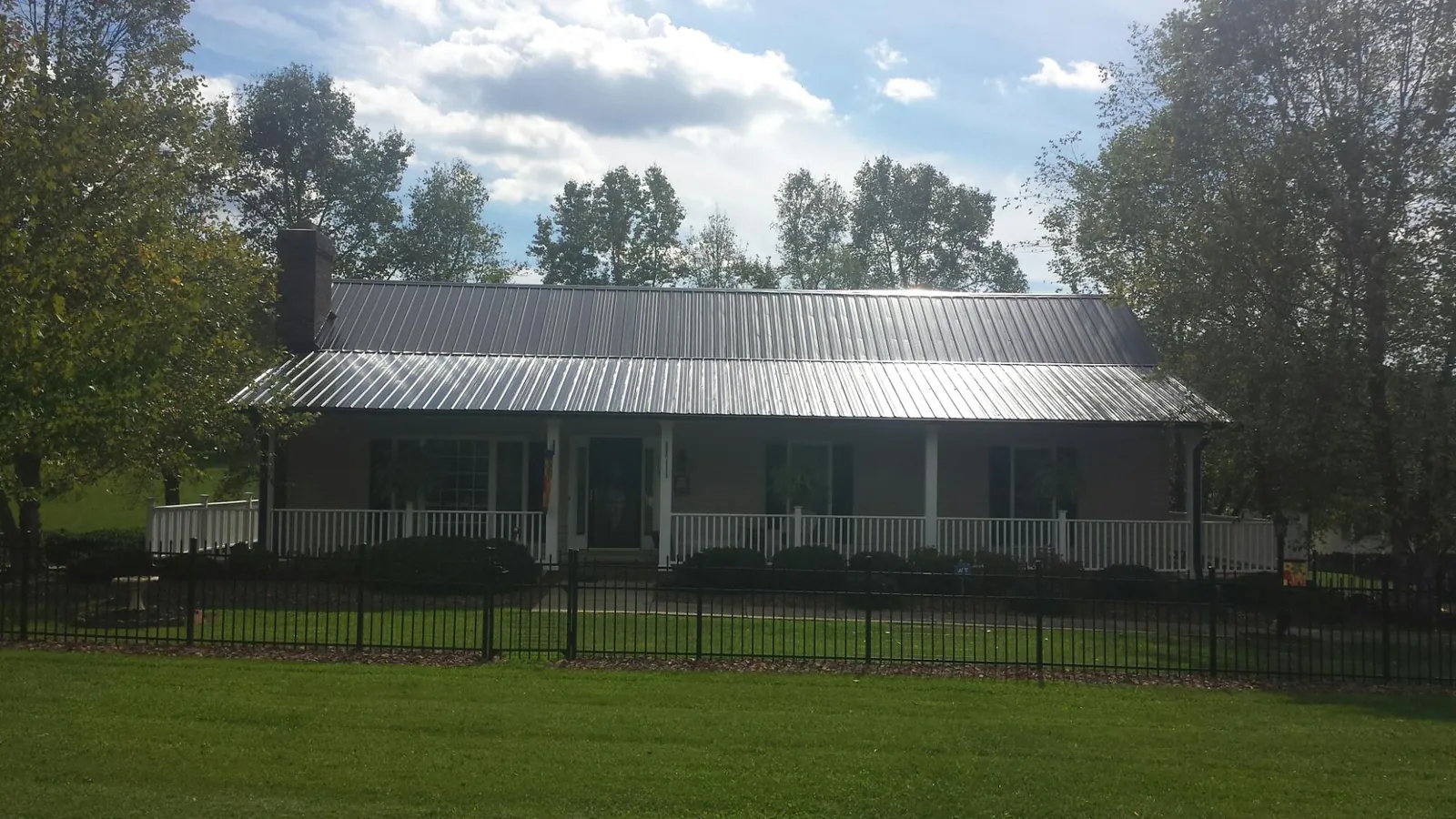 Gray metal roof on a brick ranch with a full width front porch — Gutter Guard Installation work by our crew in Killduff